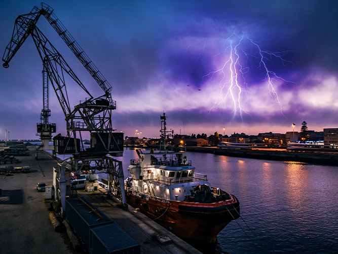 Night view of a shipping port with lightning and thunderstorm nearby