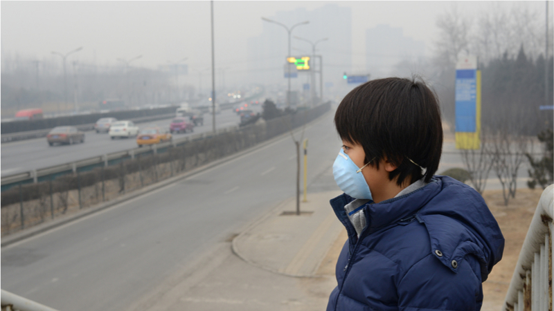 A boy in a face-mask and Smog in the city