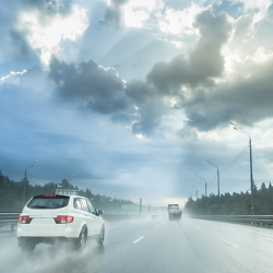 Drive car in rain on asphalt wet road. Clouds and sun.