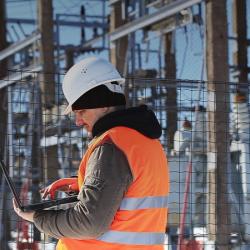 Man with laptop in front of power station